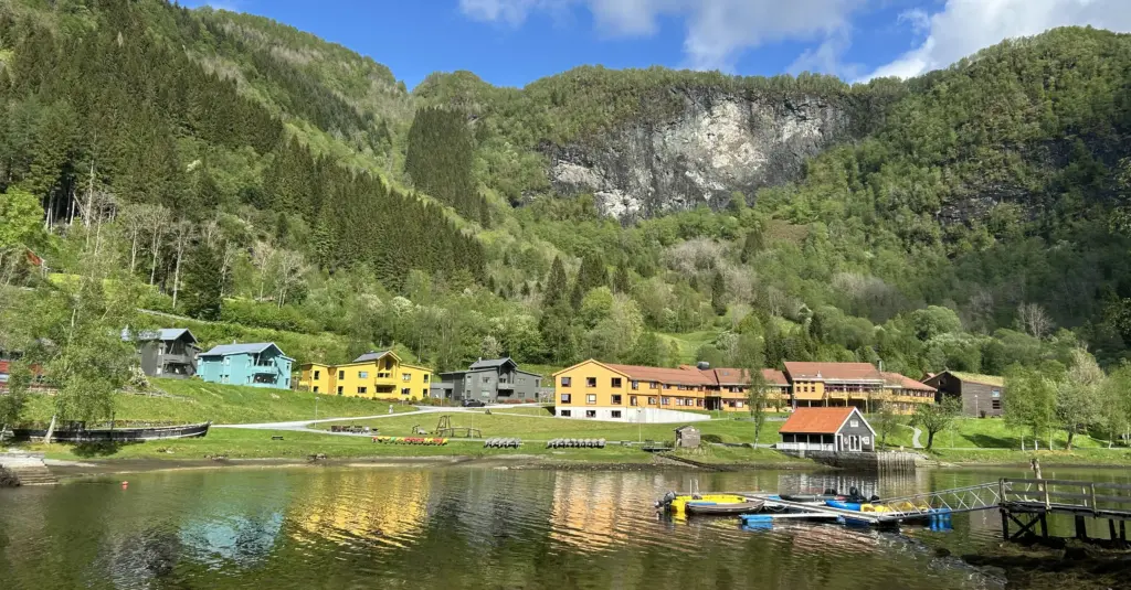 Bygningar i ulike fargar, fjord og fjell rundt. Foto.